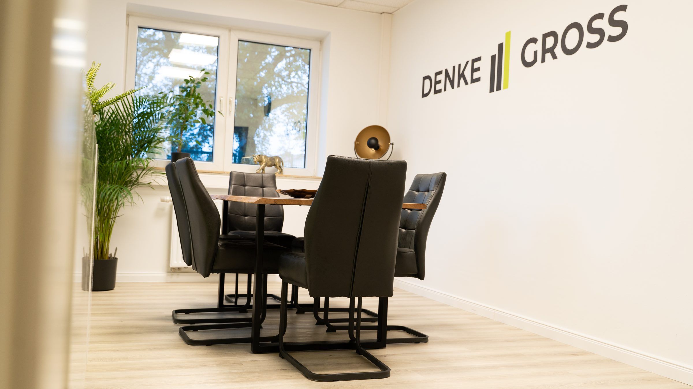 Besprechungsraum von Image Digital mit dem Schriftzug DENKE GROSS an der Wand und Blick ins Grüne.