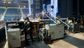 The band’s “in-ear” monitor mixer makes sure the sound is mixed properly for each musician individually. Note: the “in-ear” monitors are used by James and the musicians onstage to allow them to get individual mixes in their ears of whatever instruments or singers they would like to hear while performing. Everyone has a different preference regarding level of sound from each instrument during performance. The audio mix board in the front of the house (usually at the back of the concert hall) is where the sound mixer for the tour will mix the sound heard by the audience. (Rachel Adkins, “in-ear mixer extraordinaire”) (Photo: Michael Drazdzinski)