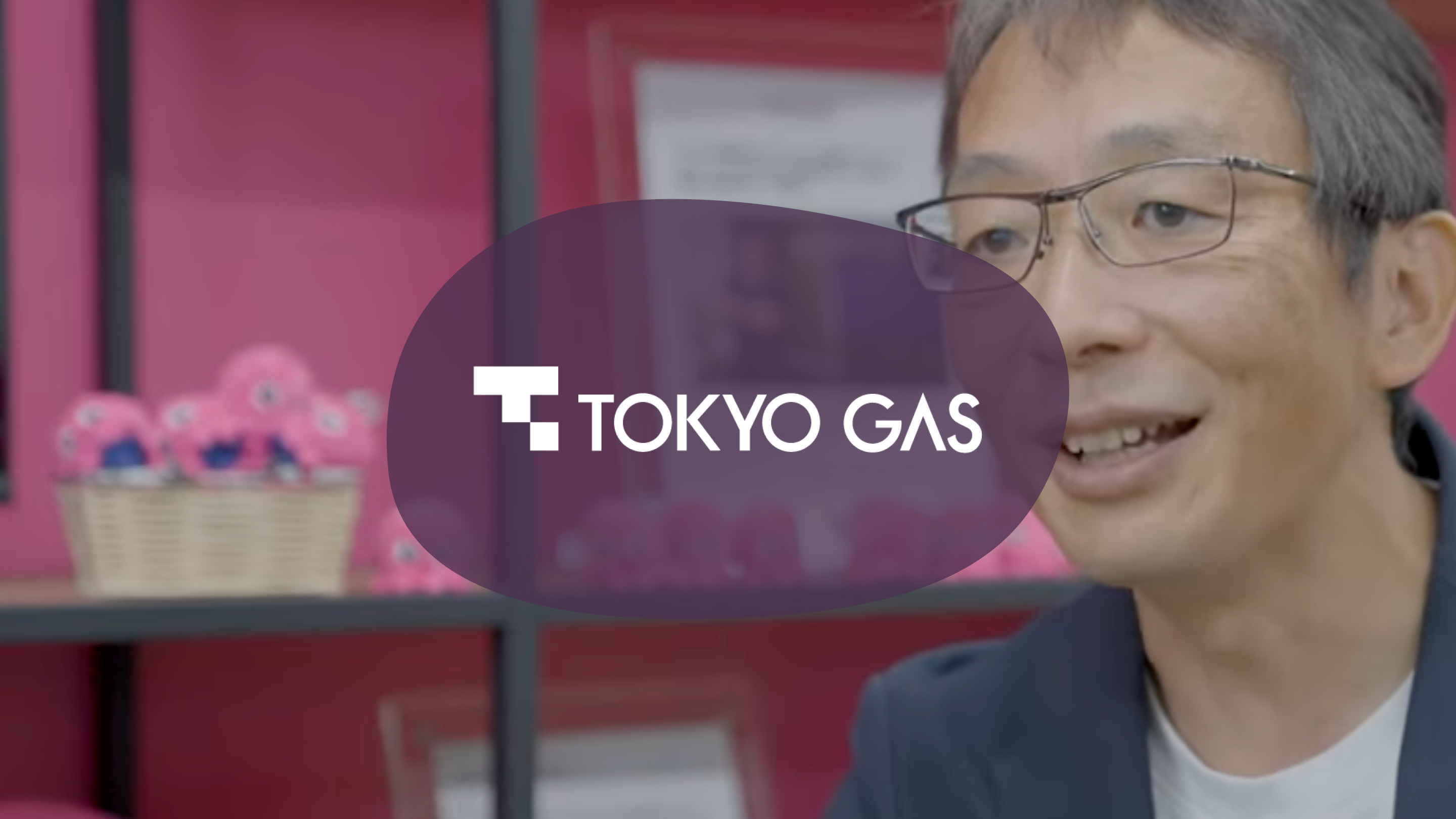 Tokyo Gas logo overlaid on an image of a smiling man wearing glasses.
