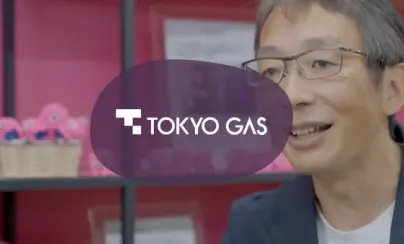 Tokyo Gas logo overlaid on an image of a smiling man wearing glasses.