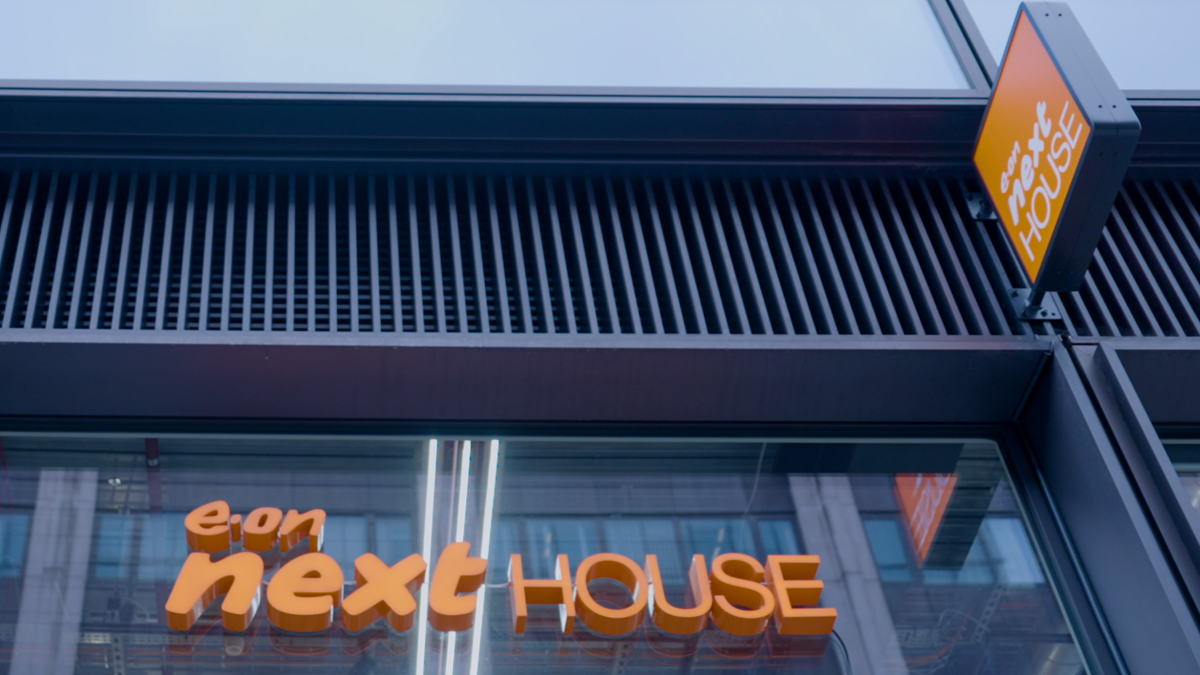 Exterior view of a building with orange "e.on next HOUSE" signage.