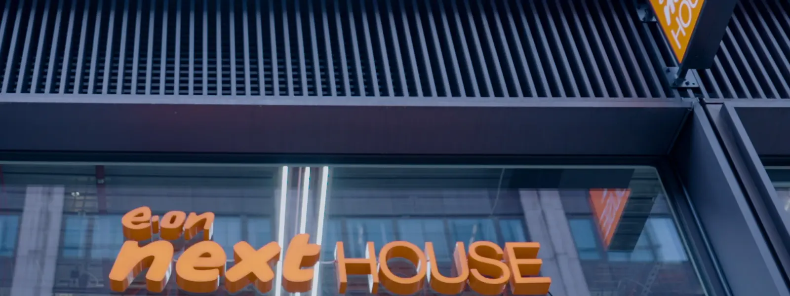 Exterior view of a building with orange "e.on next HOUSE" signage.