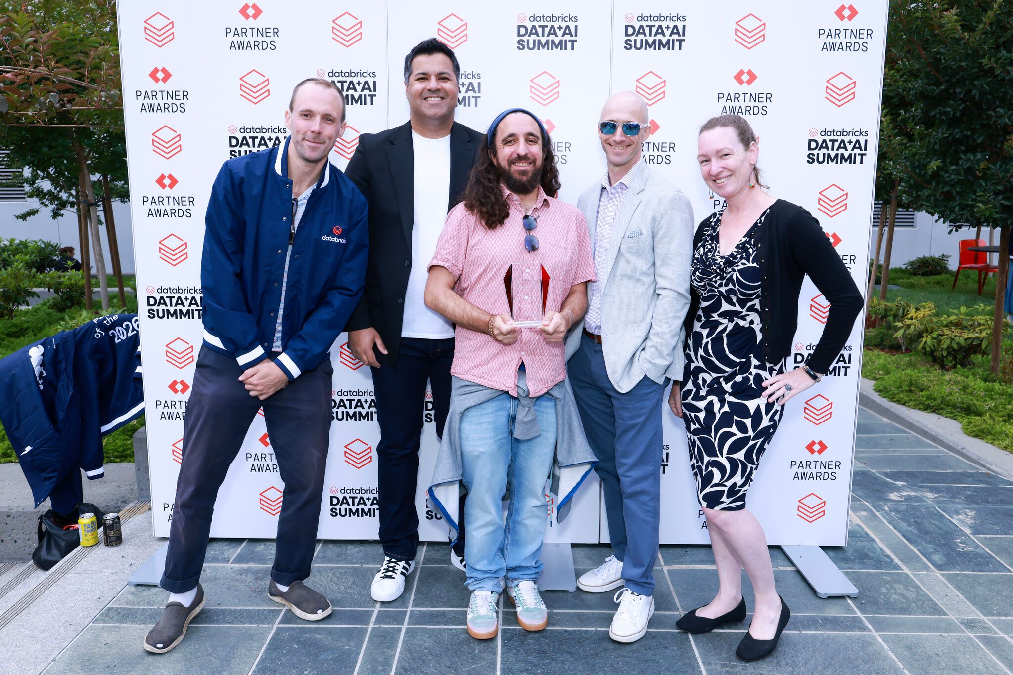 Kraken and Databricks employees stand in front of a Databricks Partner Awards banner, one holding a trophy.