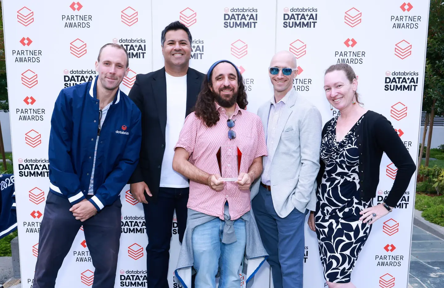 Kraken and Databricks employees stand in front of a Databricks Partner Awards banner, one holding a trophy.