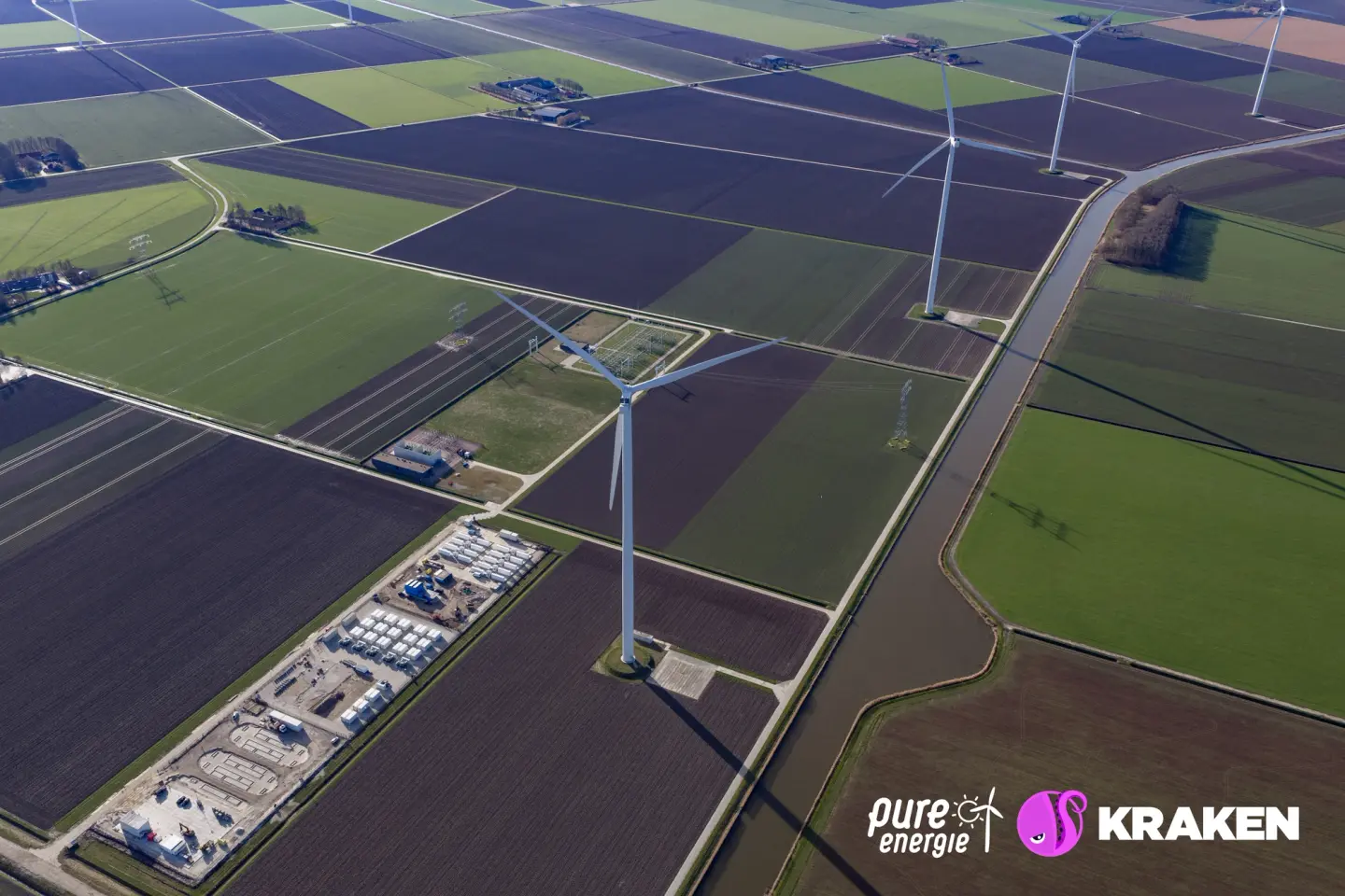 Aerial view of wind turbines in a checkerboard landscape of green and brown fields, canals, and Pure Energie's Batterij Groen in Dronten..