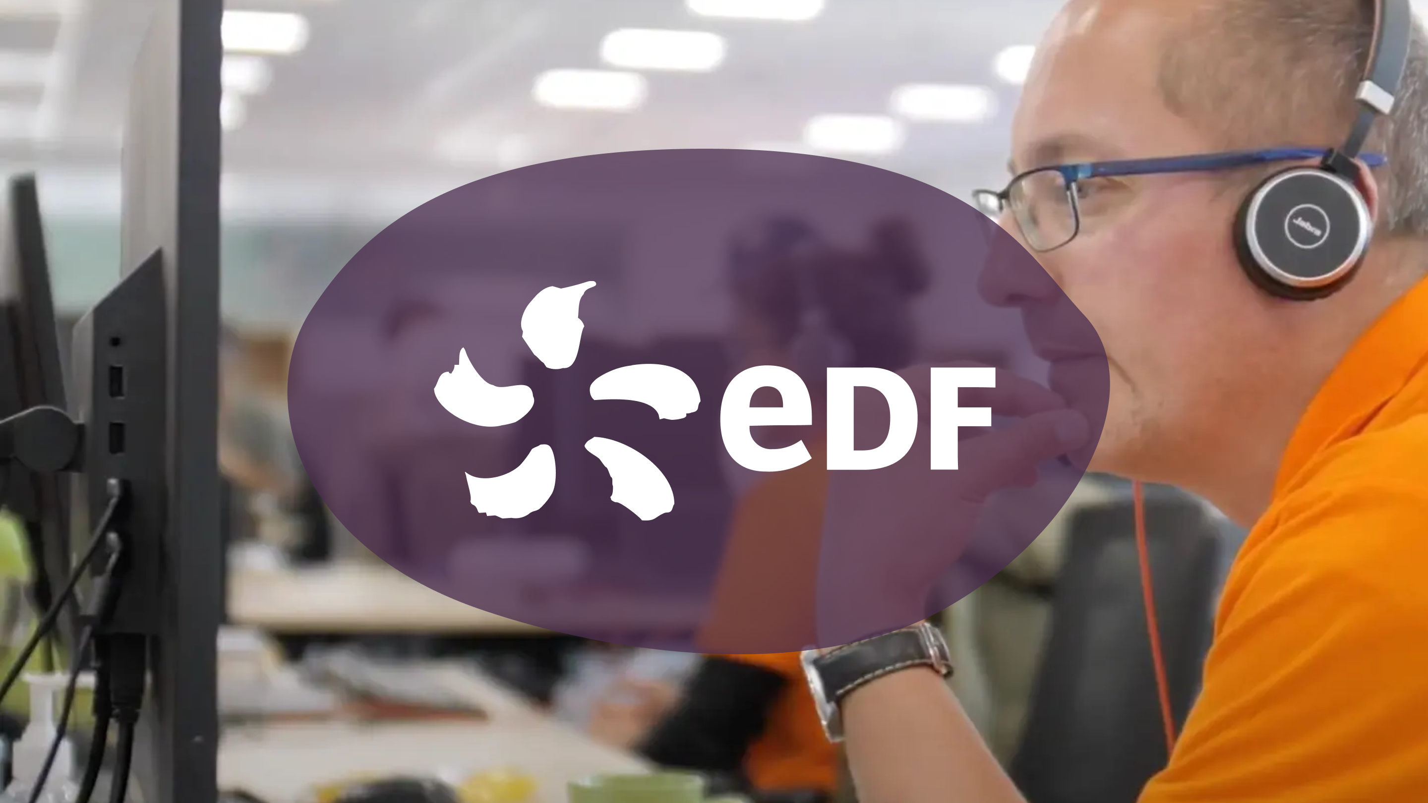 A man wearing a headset and glasses works at a computer in an office, with the EDF logo overlaid.