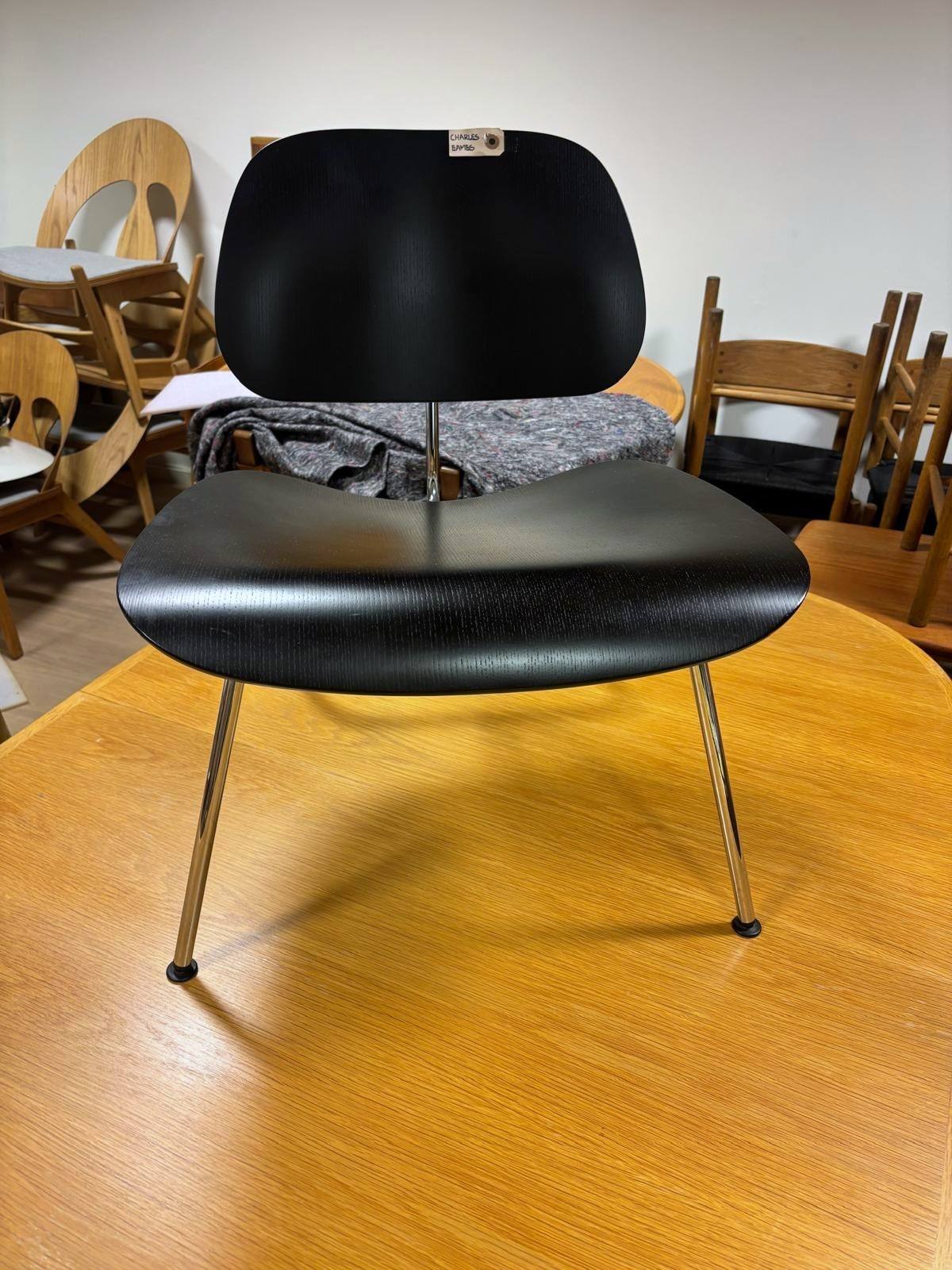 Én stol sett rett forfra, med rygg og sete i sort finer.