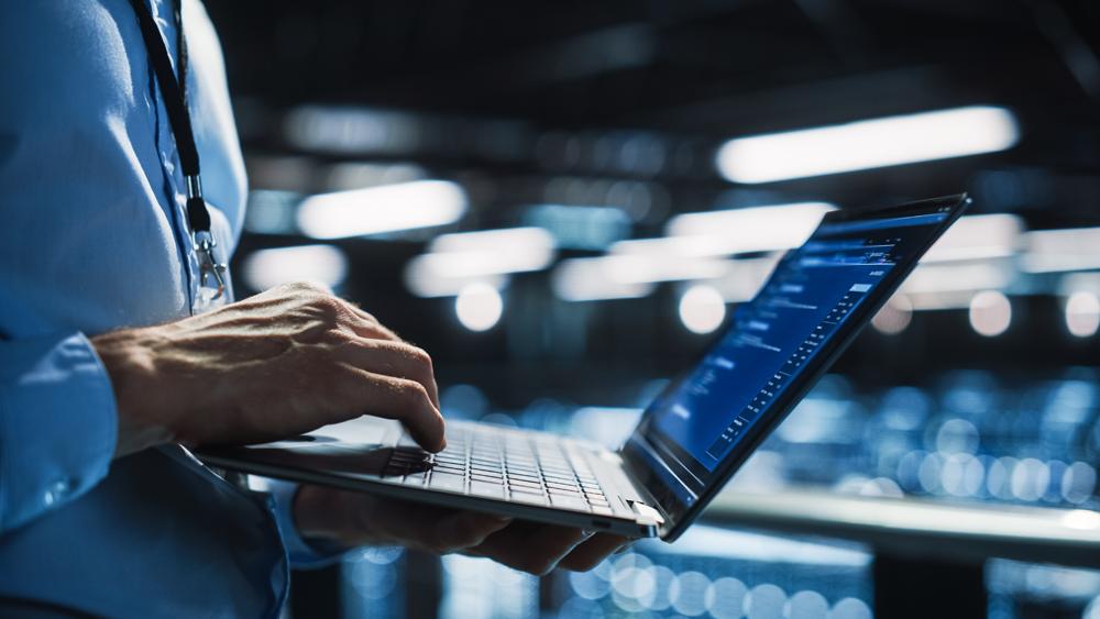 Worker holding a laptop with a blue shirt in an office