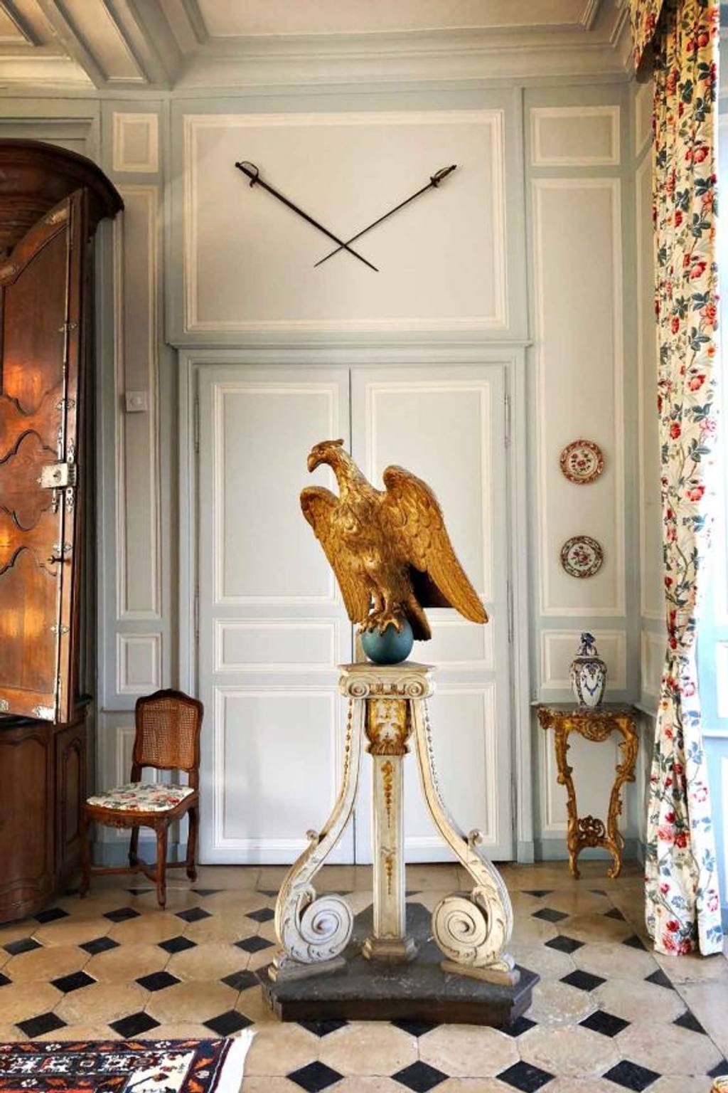 Hall with checkered marble floor, gilded eagle on a carved pedestal and crossed swords on the wall