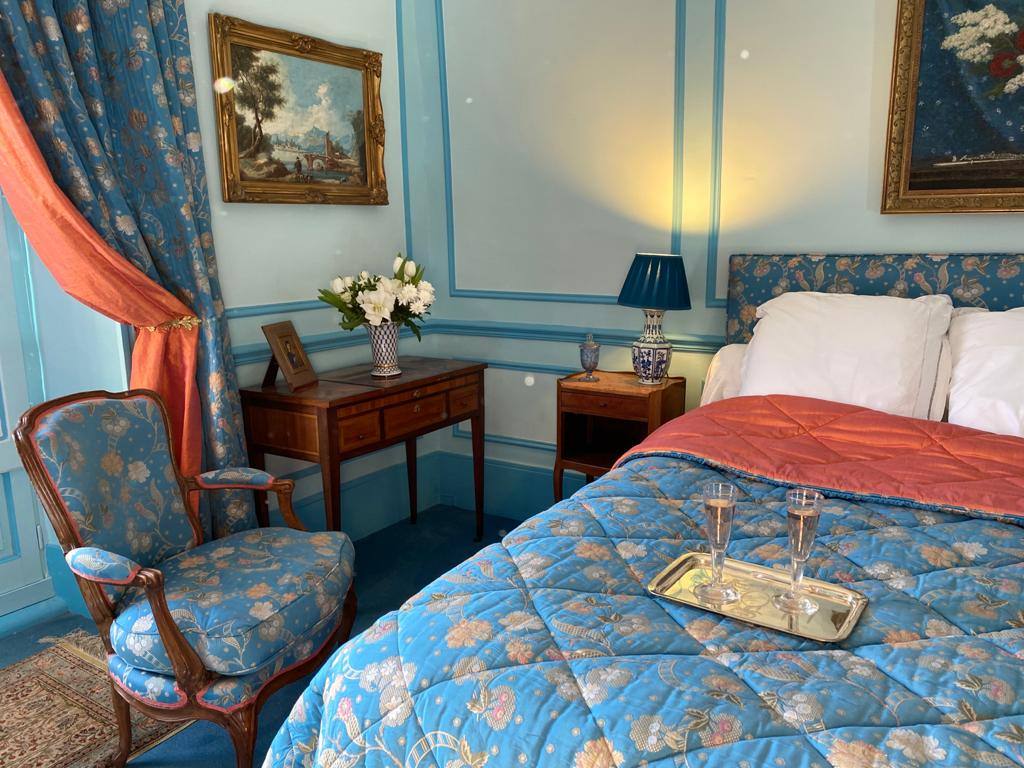 Chambre Turquoise: blue quilted bed with two flutes of sparkling wine on a silver tray, armchair and side table