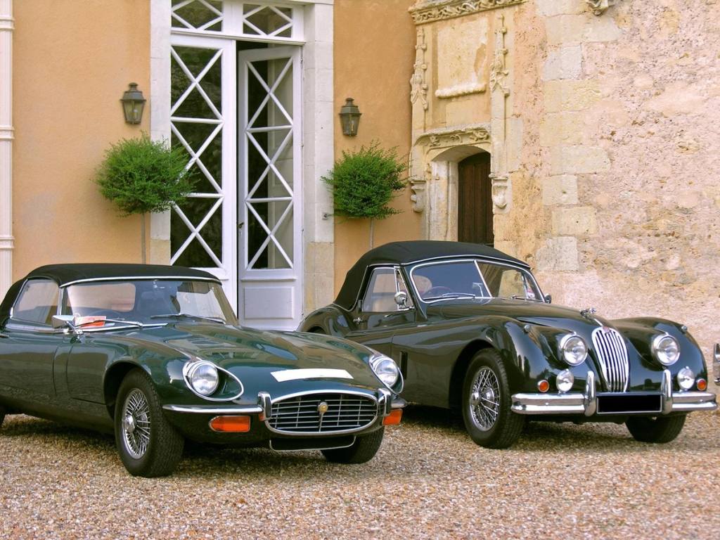 Deux cabriolets Jaguar anciens garés sur le gravier devant l'entrée du château