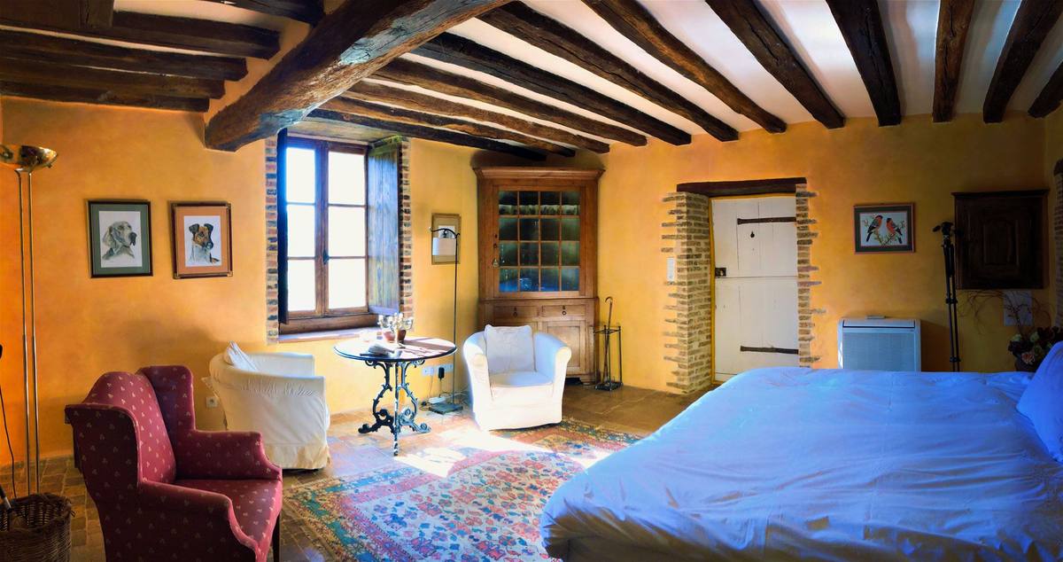 Beamed room in Cottage Les Glycines with armchairs, a corner cupboard, a rug and the bed