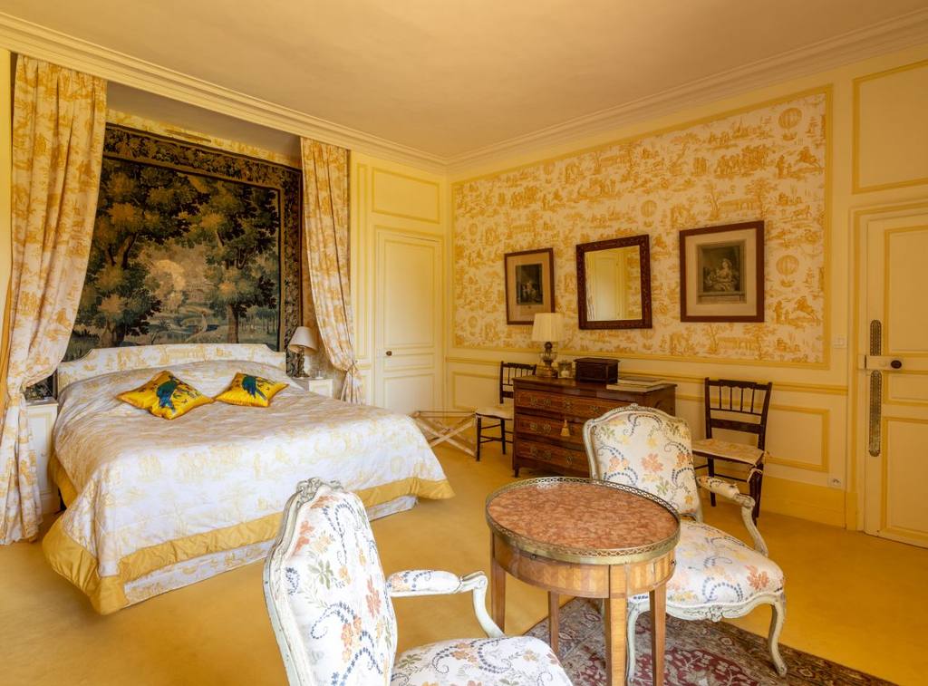 Chambre Jaune: bed beneath a tapestry, yellow toile de Jouy walls and Louis XV armchairs