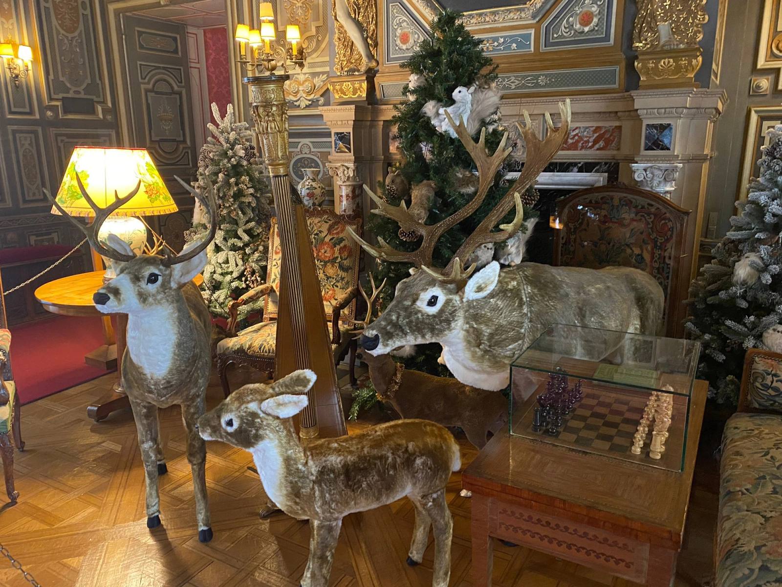 Salon décoré pour Noël avec des rennes en peluche, un sapin et une lampe allumée