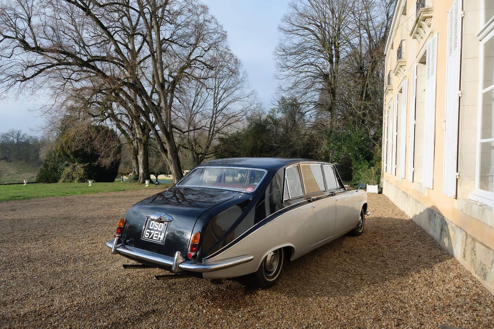 Zweifarbige Oldtimer-Limousine auf dem Kies entlang der Schlossfassade
