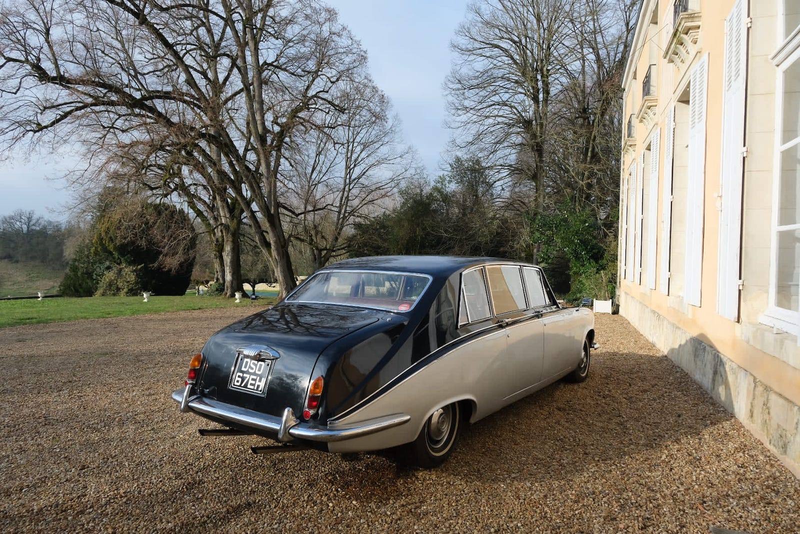 Zweifarbige Oldtimer-Limousine auf dem Kies entlang der Schlossfassade