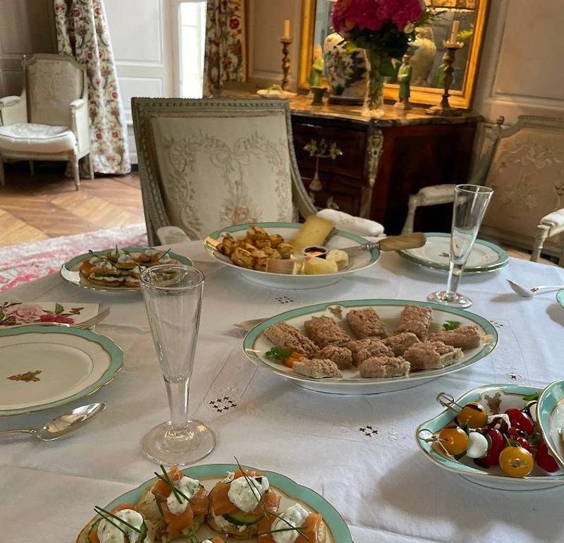 High tea table in a salon: canapés, sandwiches, cheese and champagne flutes on green-rimmed porcelain