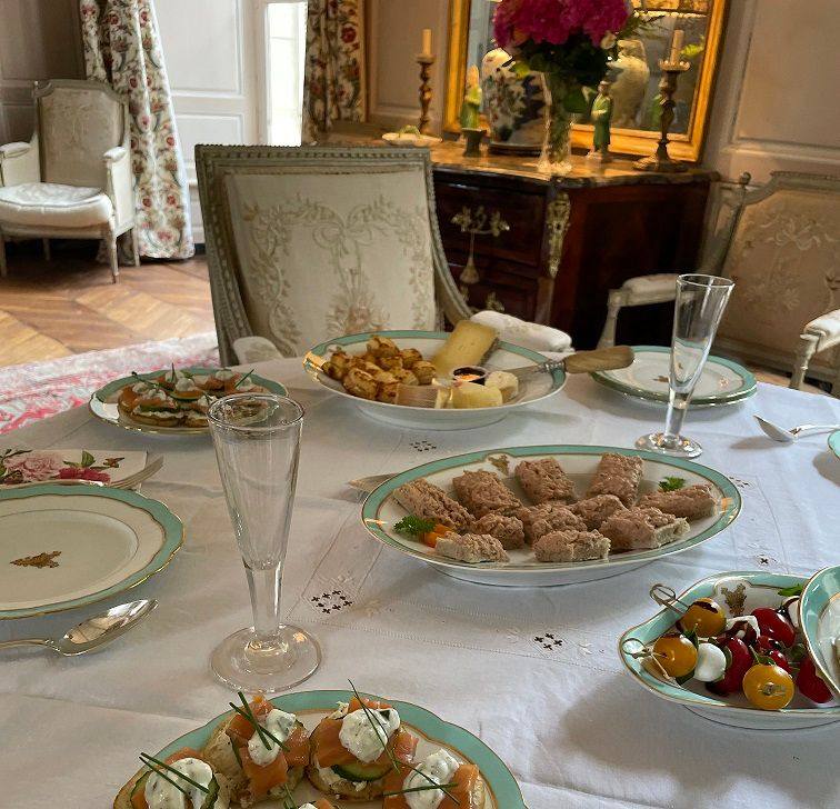 High-Tea-Tafel im Salon: Canapés, Sandwiches, Käse und Champagnerflöten auf Porzellan mit grünem Rand
