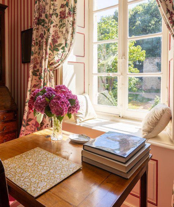 Rosa Hortensien und Bücher auf einem Schreibtisch am sonnigen Fenster der Chambre aux Fleurs
