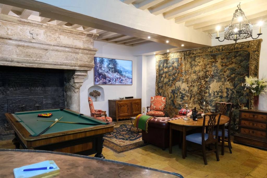 Pièce à Feu: billiard table before a monumental stone fireplace, with a large tapestry