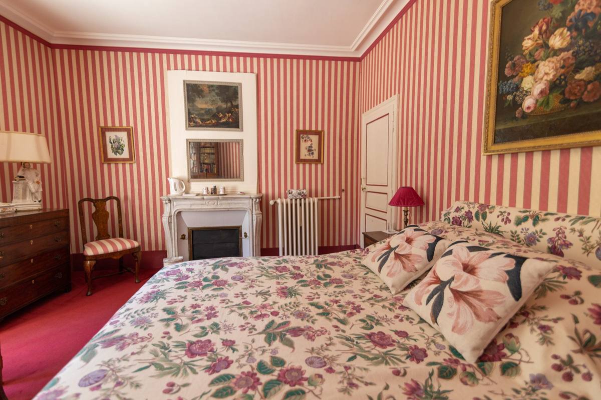 Chambre aux Fleurs: floral bedspread facing a white marble fireplace, red-and-white striped walls