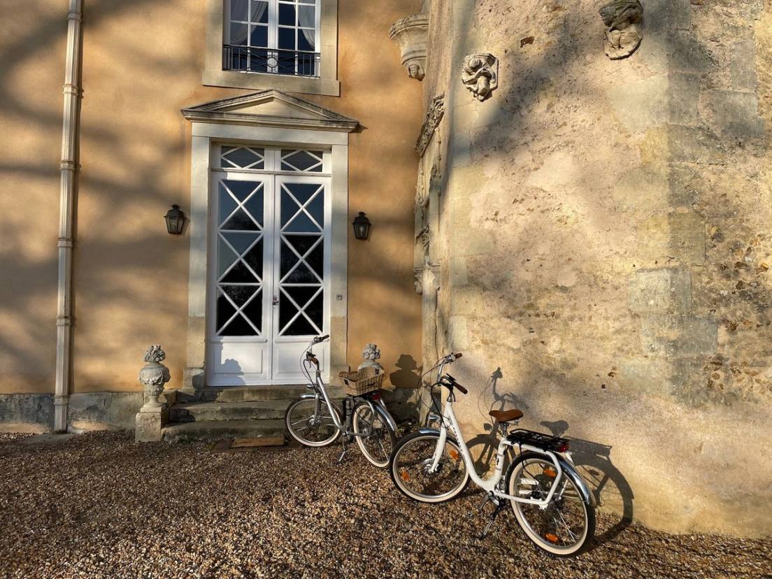 Deux vélos blancs au pied du perron du château, dans la lumière rasante