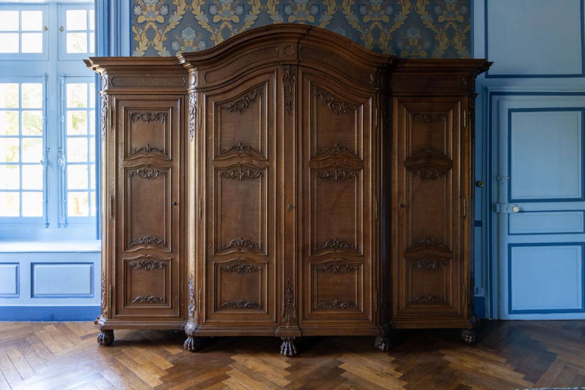 Imposing carved wooden armoire against blue panelling in the Suite Marin de Vanssay