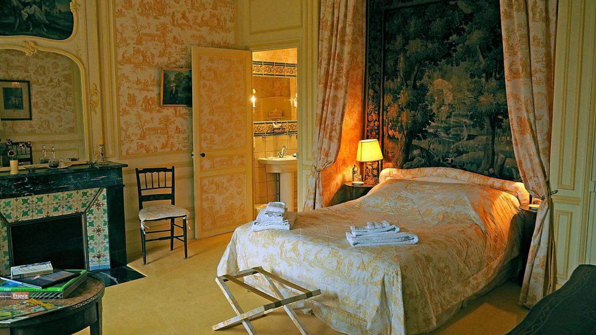 Chambre Jaune: bed before a tapestry, yellow toile walls, fireplace and open door to the bathroom