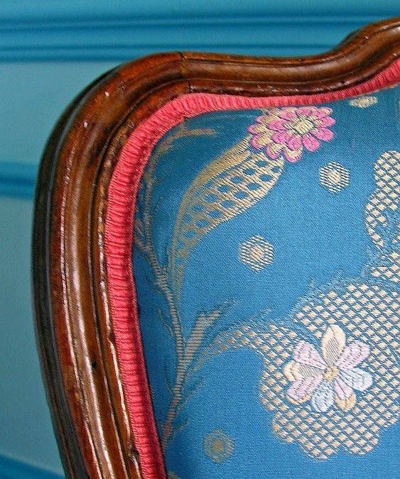 Detail eines geschnitzten Holzsessels mit blauem, geblümtem Seidenbrokat und rosa Borte