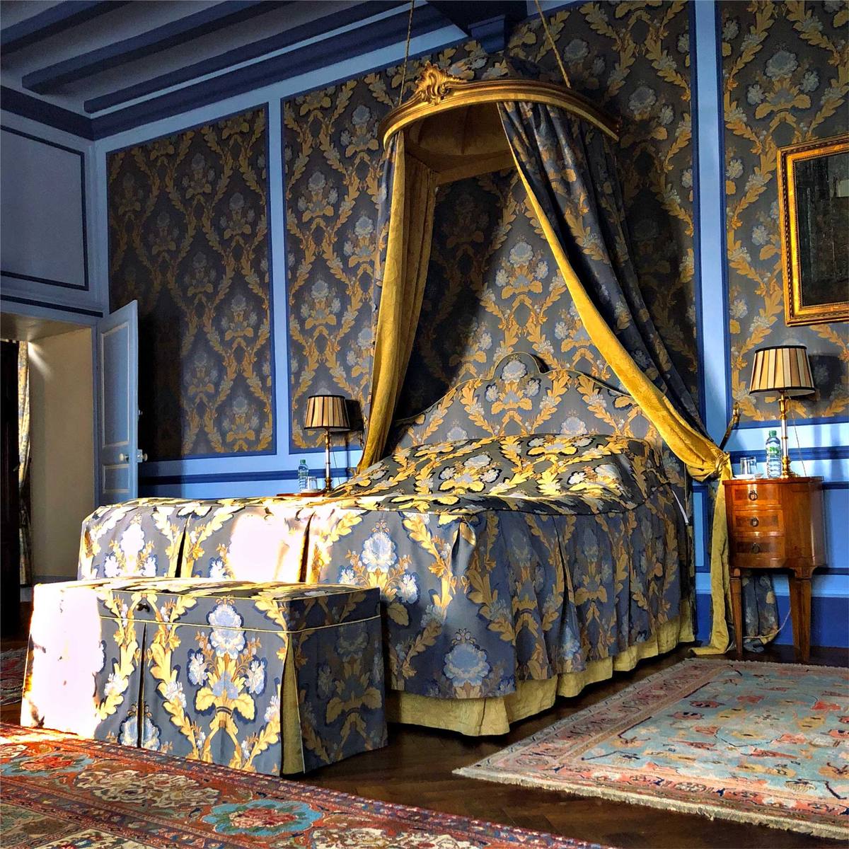 Suite Marin de Vanssay: canopy bed with gold-lined drapes and matching bench, blue damask walls