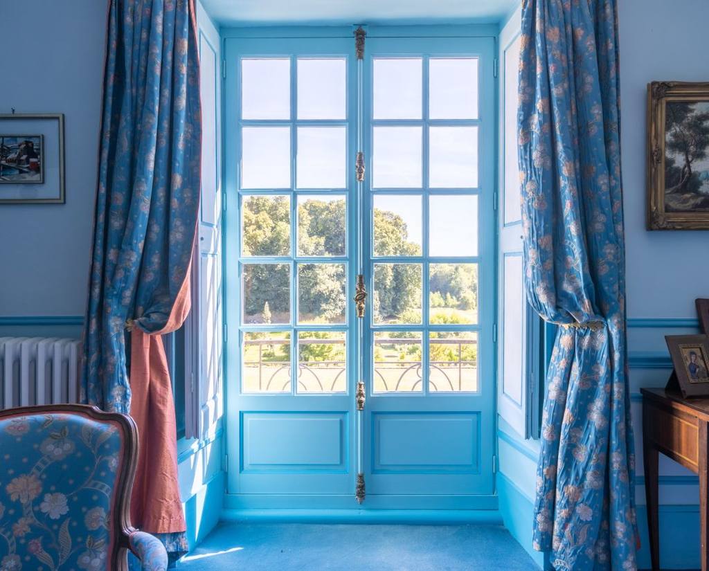 French window framed by blue floral curtains opening onto the park, Chambre Turquoise