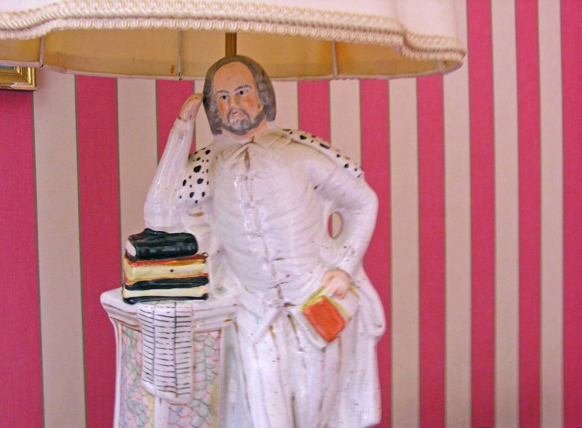Porcelain figure lamp of a bearded gentleman holding a book, against pink striped wallpaper, Chambre aux Fleurs
