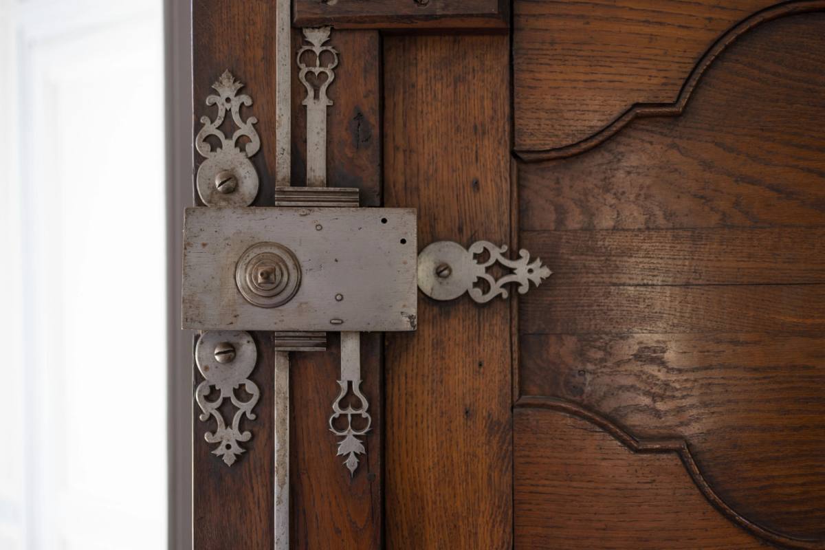 Grande Salle à Manger: ornate antique lock with scrolled escutcheons on a carved wooden door