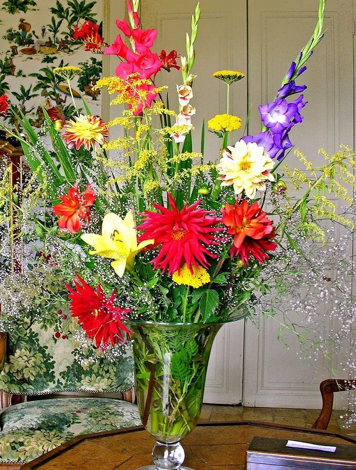 Grand bouquet d'été de glaïeuls, dahlias et lys dans un vase en verre, dans le vestibule