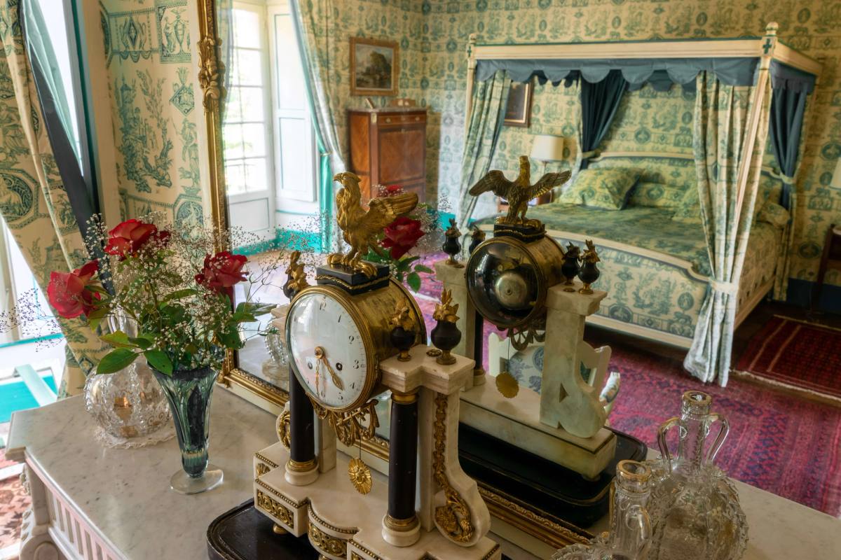 Mantel clocks and red roses, the canopy bed reflected in the mirror, Chambre Esprit de Jouy Verte