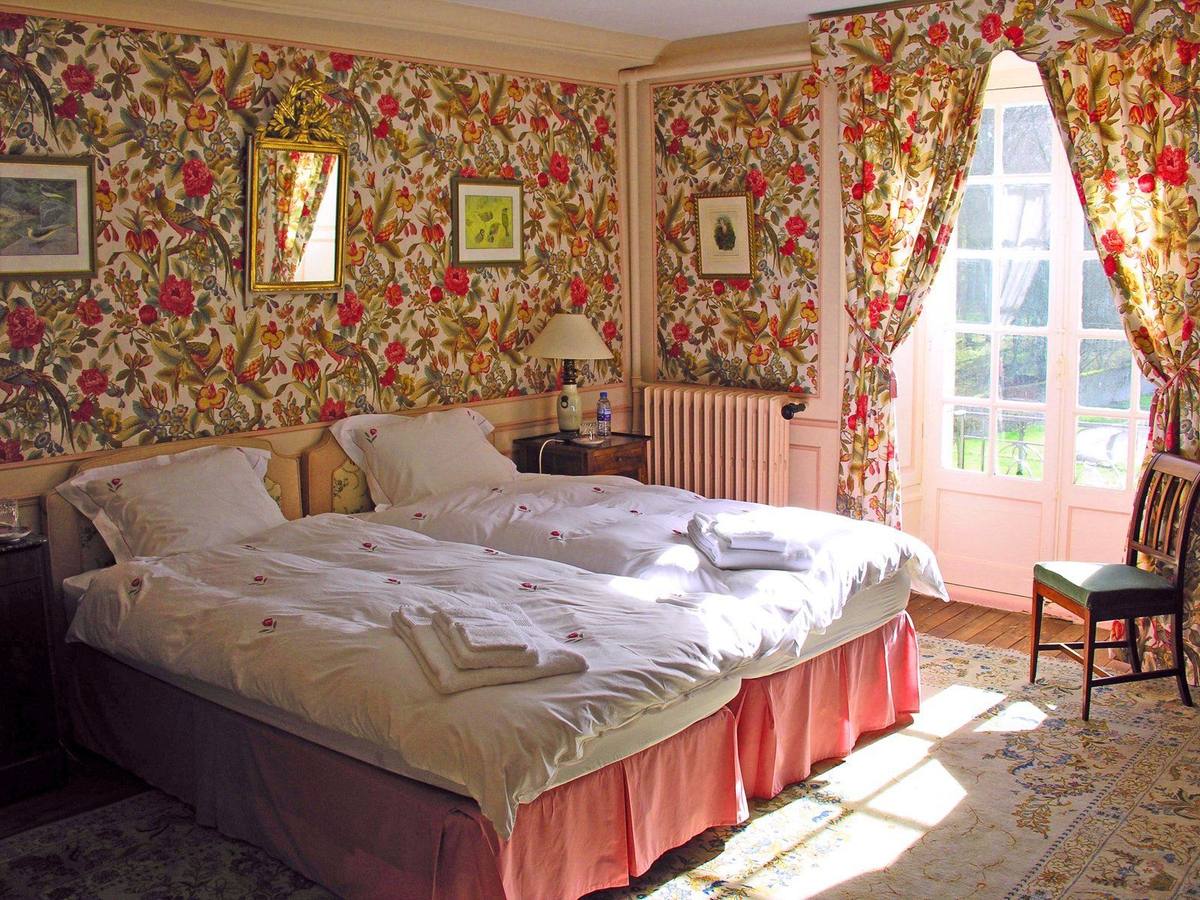 Chambre aux Oiseaux: sunlit bedroom with floral wallpaper and curtains, beds with folded towels