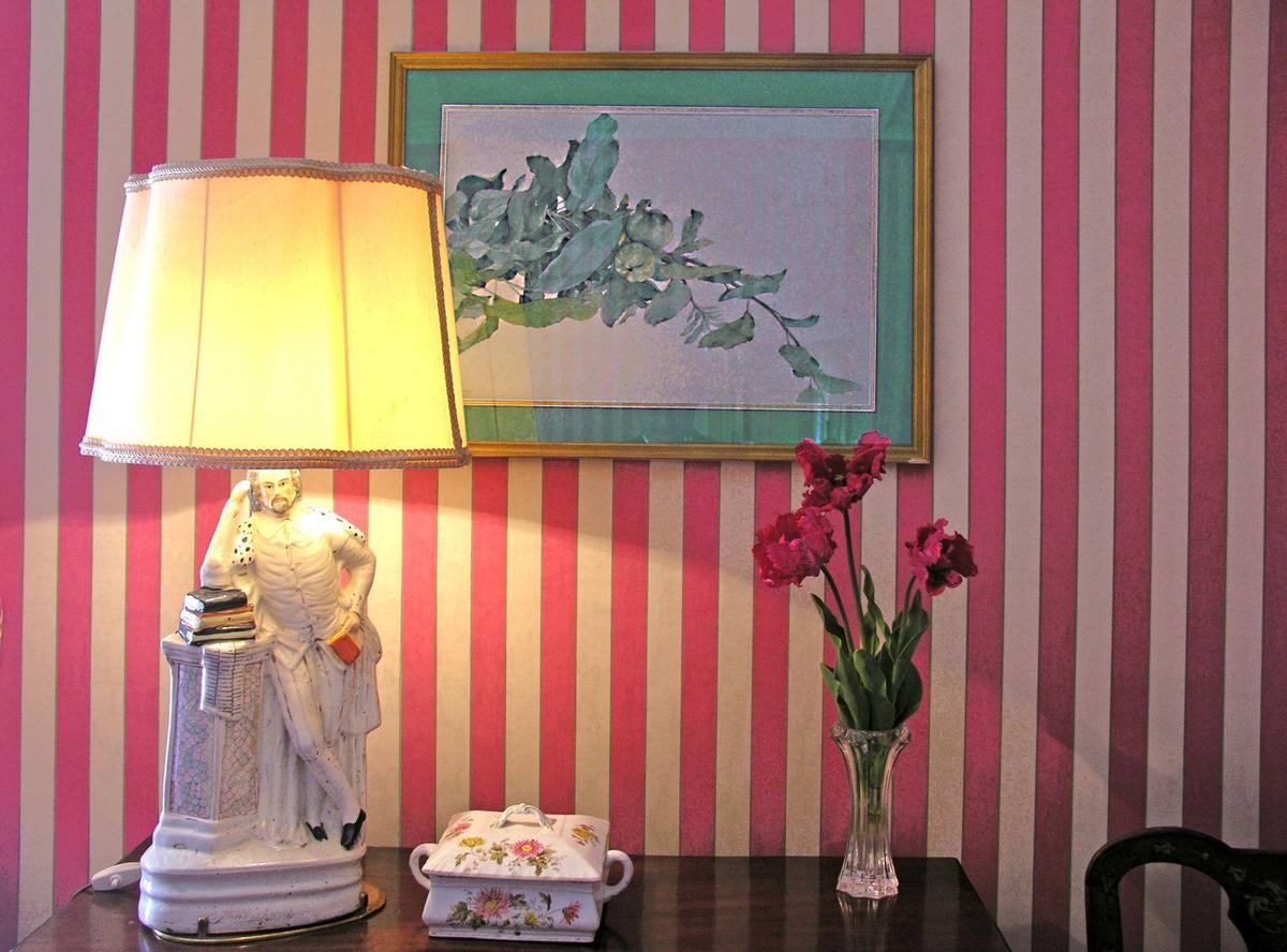 Chambre aux Fleurs: pink-striped wall, Shakespeare figurine lamp, botanical watercolour, red flowers