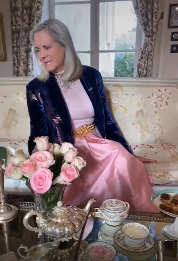 Die Gastgeberin in Samtjacke und rosa Satinrock beim High Tea, mit Rosen und silbernem Teeservice