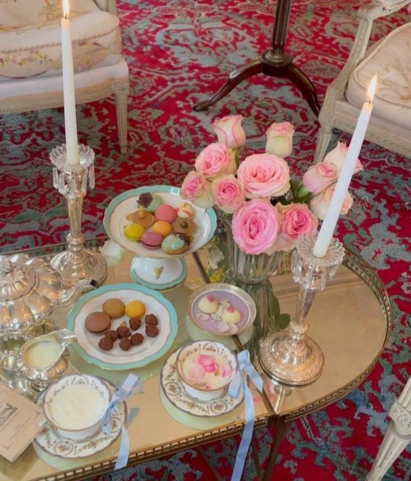 High tea in the salon: macarons, silver tea service, pink roses and candles on a low table