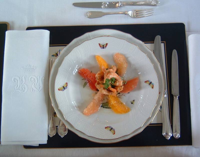 Starter of salmon and citrus segments on butterfly porcelain, with silver cutlery and monogrammed napkin