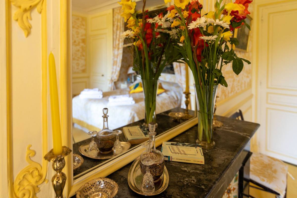 Chambre Jaune: yellow and red flowers, candle and crystal carafes on the mantelpiece