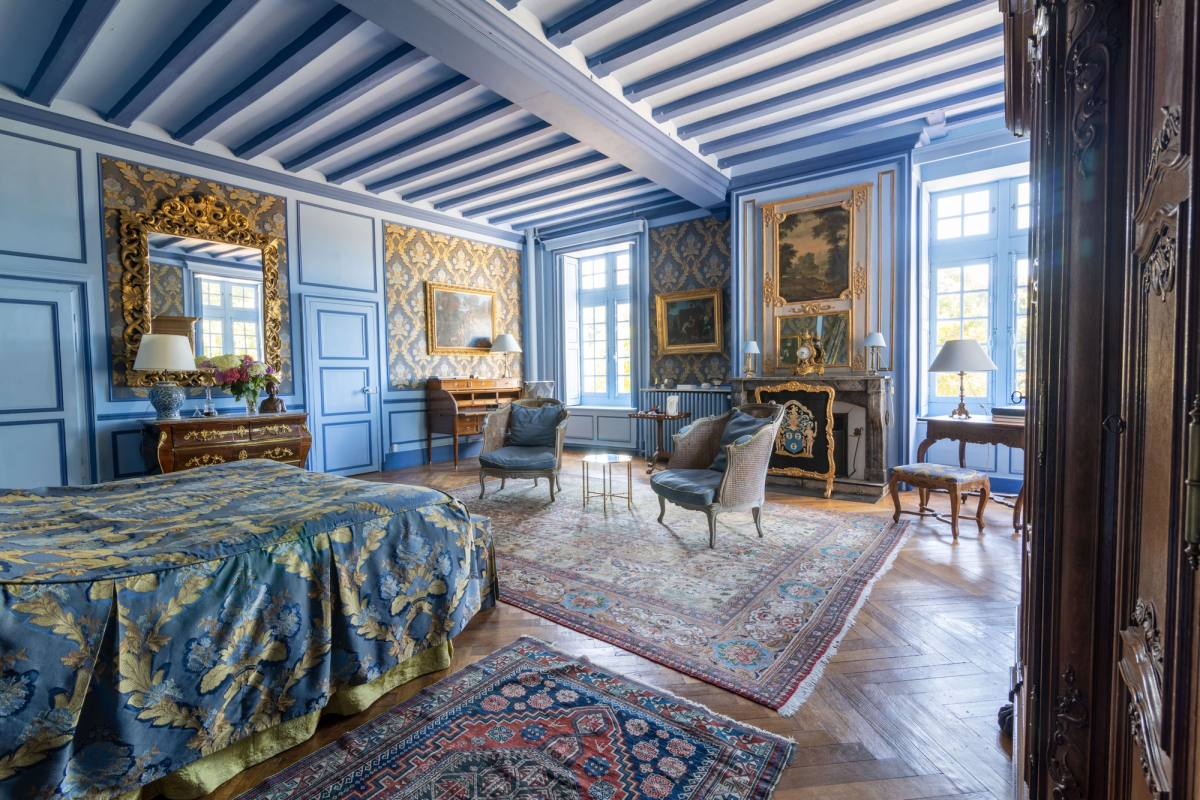 Chambre Marin de Vanssay seen from the door: bed, beamed blue ceiling, rugs and armchairs