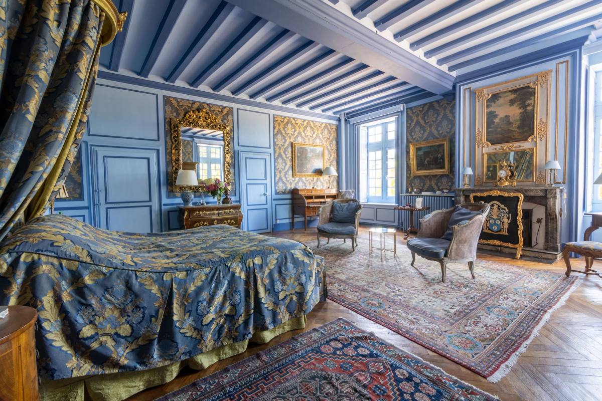 Suite Marin de Vanssay: canopy bed in blue-and-gold damask, beamed ceiling, fireplace and gilt mirrors