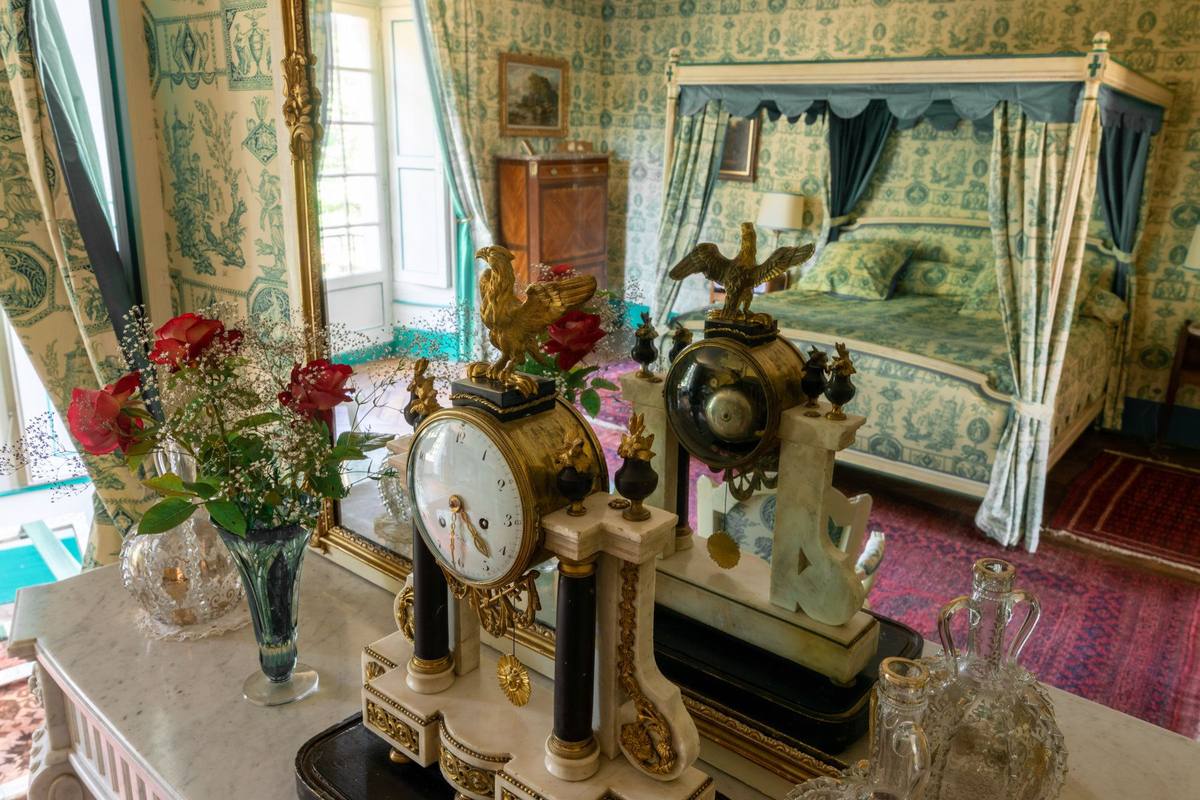 Mantel clocks and red roses, the canopy bed reflected in the mirror, Chambre Esprit de Jouy Verte