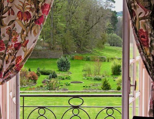 View from the Oiseaux room window: floral curtains, wrought-iron railing and the park lawns