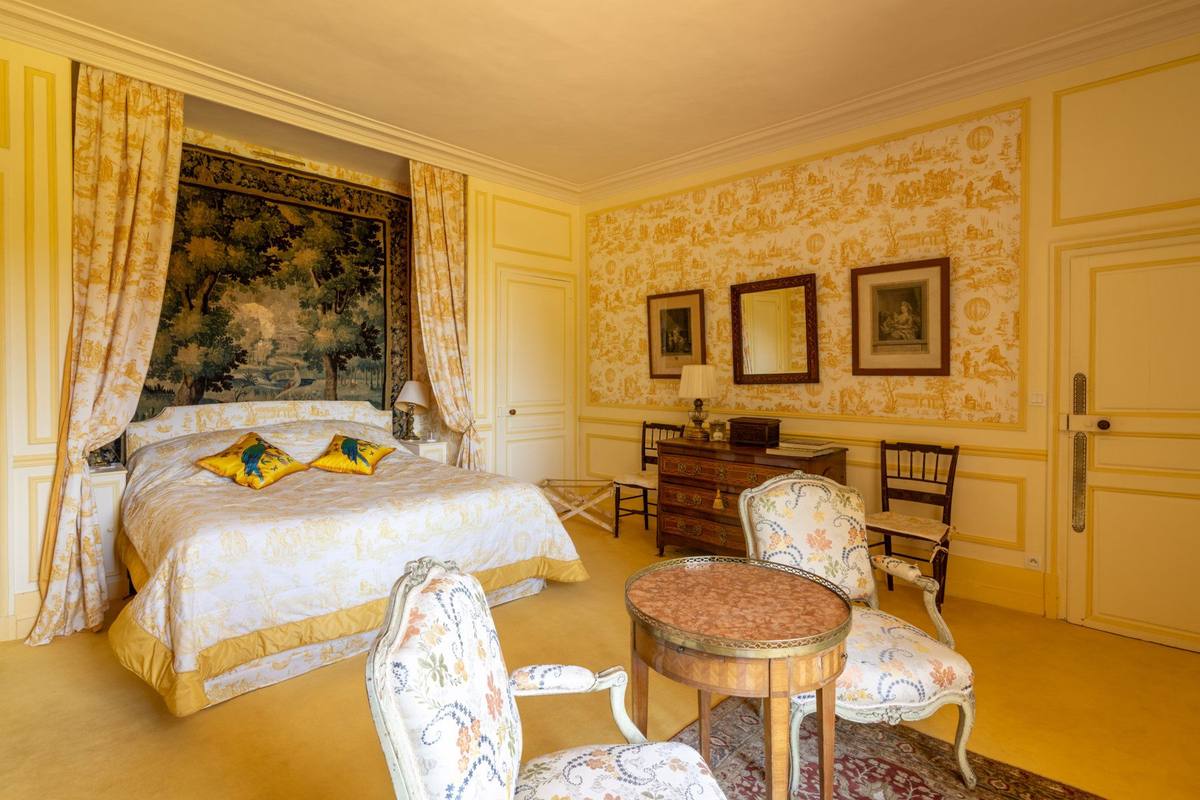 Chambre Jaune: bed beneath a tapestry, yellow toile de Jouy walls, gueridon and armchairs