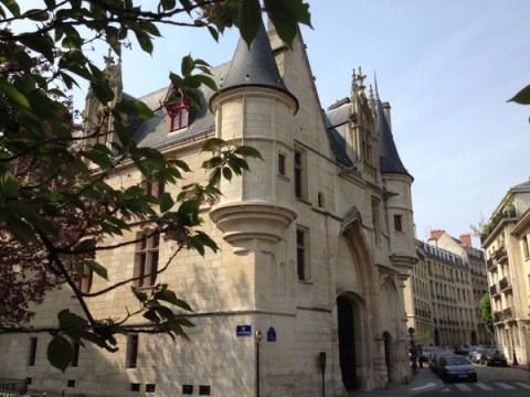 Late-Gothic turreted mansion on a Paris street corner, framed by spring foliage