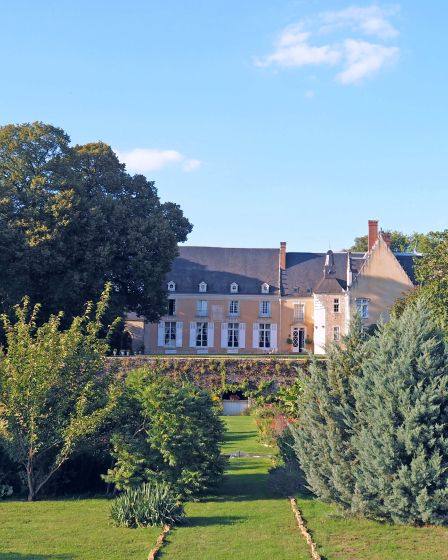 The château's façade seen across the gardens and lawns on a sunny day