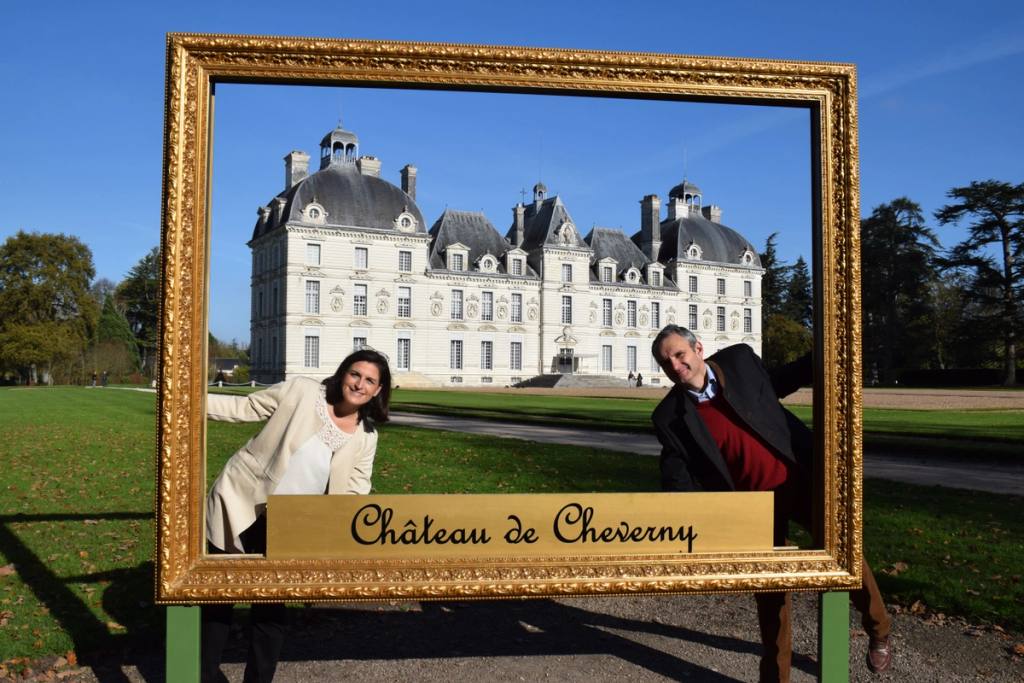 Un couple pose dans un grand cadre doré sur la pelouse du château de Cheverny