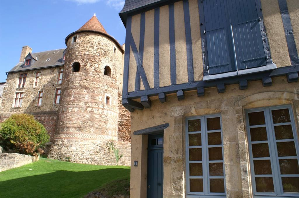 Muraille antique en pierre et sa tour ronde à côté d'une maison à colombages dans une vieille ville